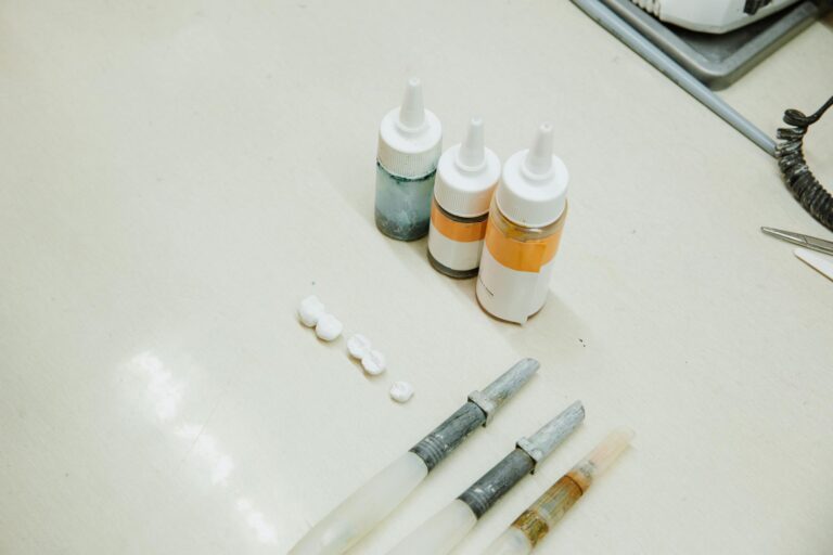 Assorted dental tools and bottles on a clean white table in a dental laboratory.